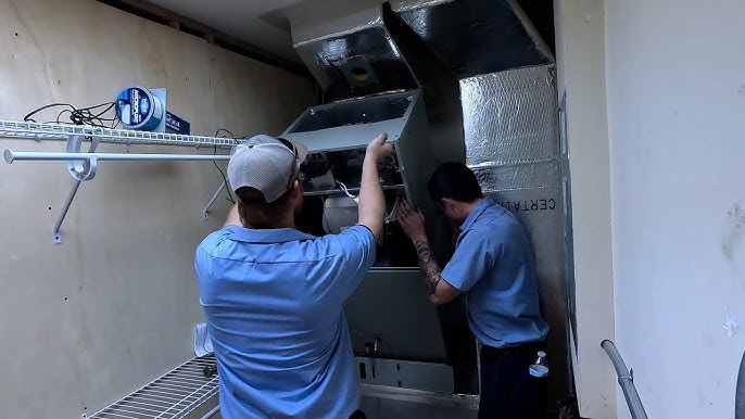 HVAC technicians installing a new heating and cooling system inside a home.